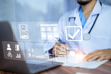 A doctor using a laptop with various icons