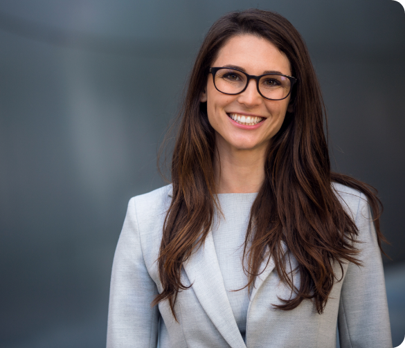 A confident, professional woman in glasses and a suit, smiling.