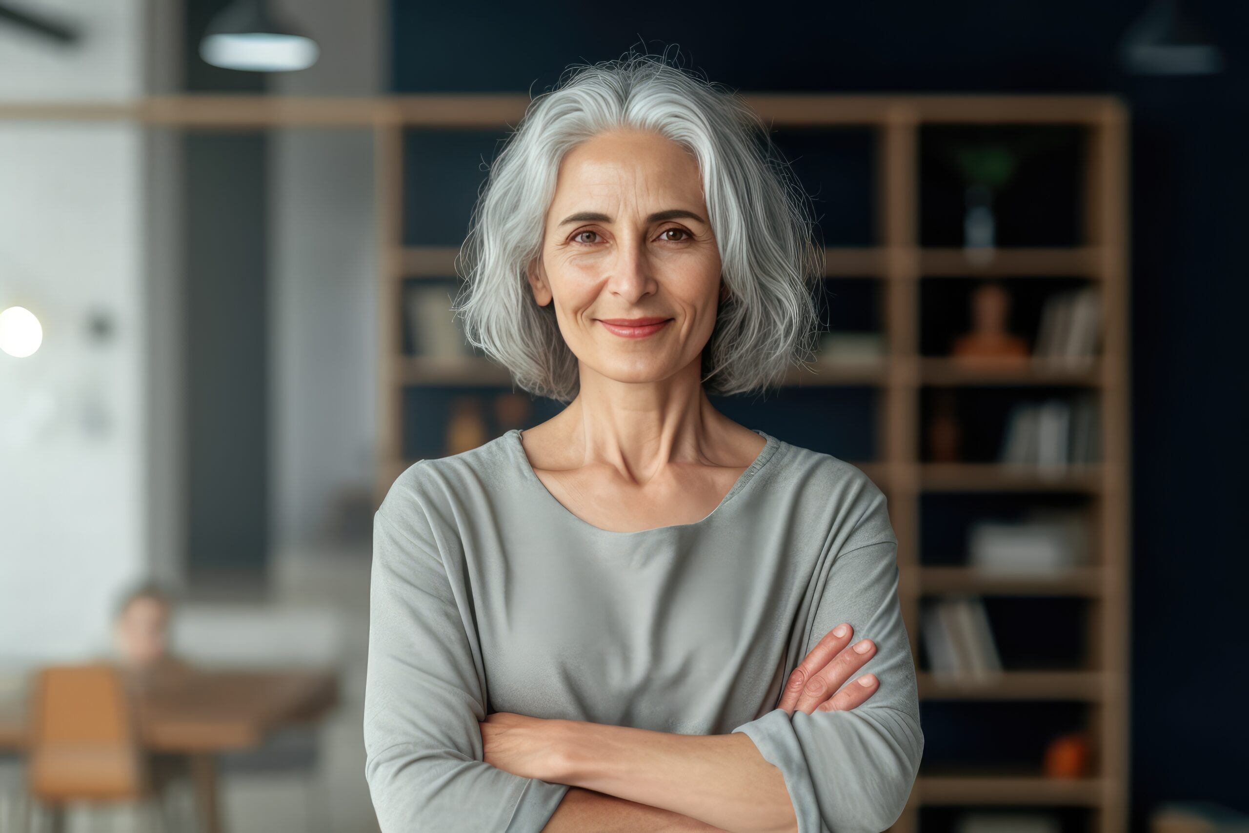 A mature woman stands confidently in front of a bookcase