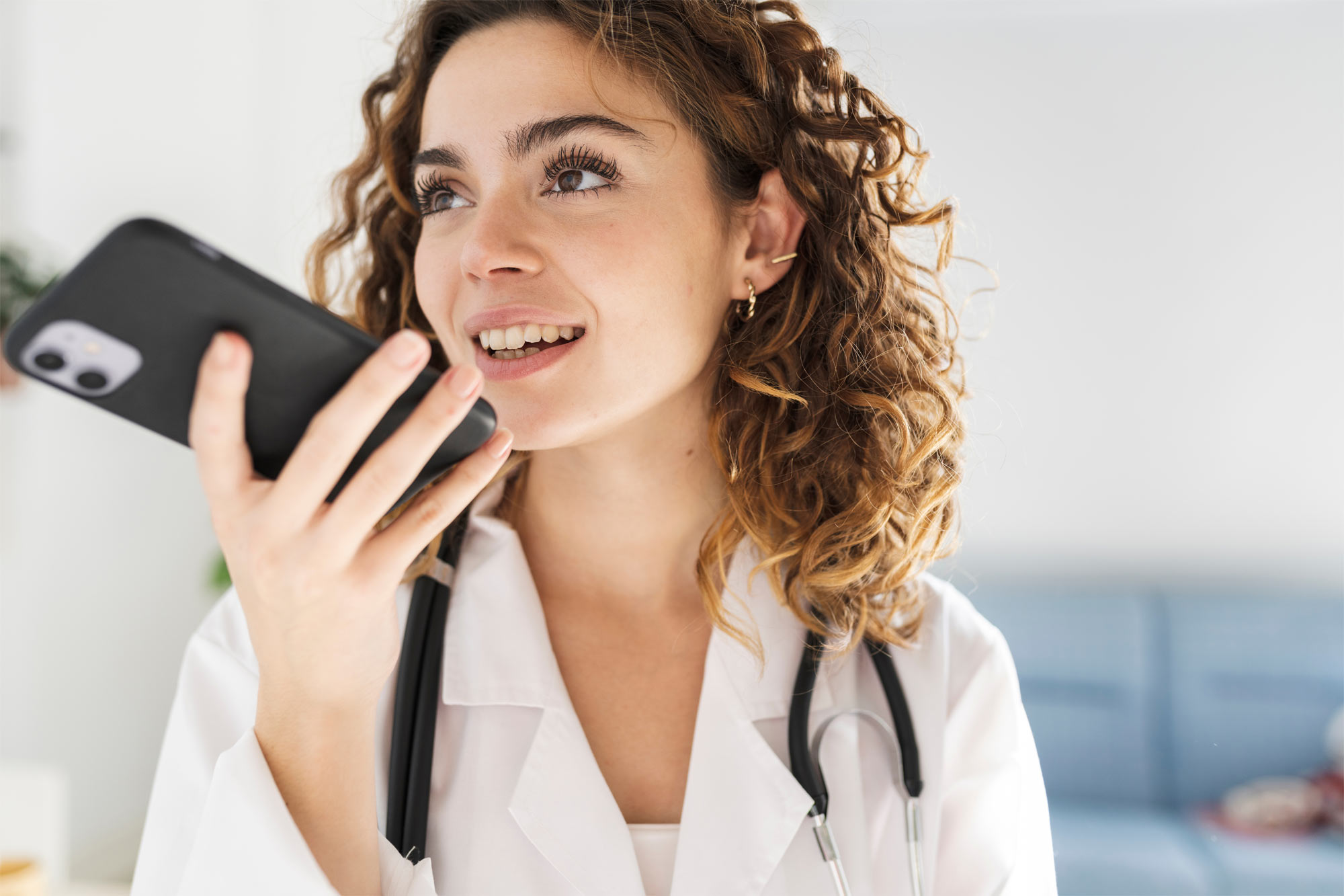 Female doctor in white coat using smartphone for medical records